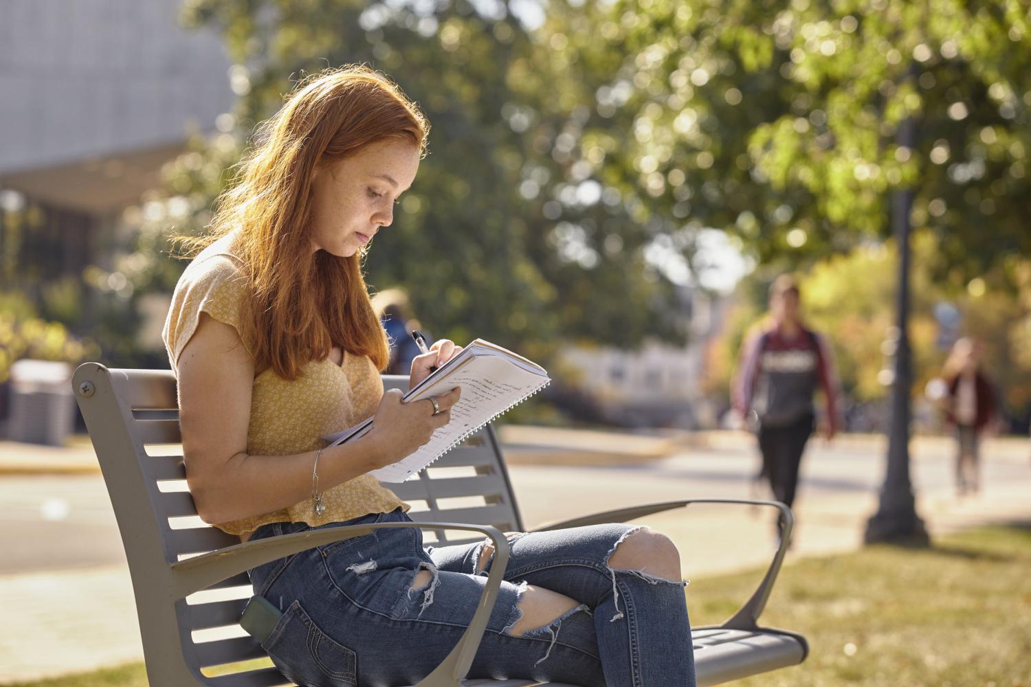 A <a href='http://kgc0kveb.8221sf.com'>全球十大赌钱排行app</a> student reads on a bench along Campus Drive.